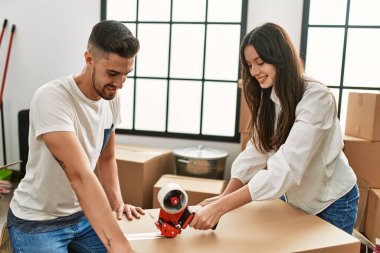 Genç İspanyol çift mutlu bir şekilde gülümsüyor. Yeni evlerinde karton kutu paketliyorlar..