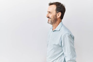 Orta yaşlı, sakallı, yalıtılmış arka planda duran, profiline bakan, doğal yüzüyle poz veren ve kendinden emin gülümseyen İspanyol bir adam.. 