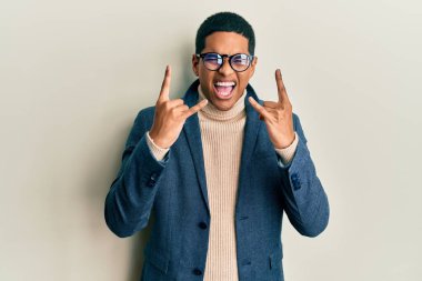 Zarif kıyafetler giymiş, gözlüklü, çılgın bir ifadeyle bağıran yakışıklı İspanyol adam elleri havada rock sembolü yapıyor. Müzik yıldızı. ağır kavram. 