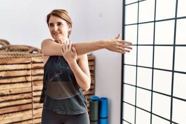 Orta yaşlı İspanyol kadın gülümsüyor spor merkezinde esniyor.