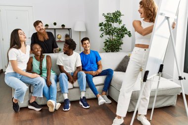 Bir grup genç arkadaş gülümseyerek evde çizim oyunu oynuyorlar..