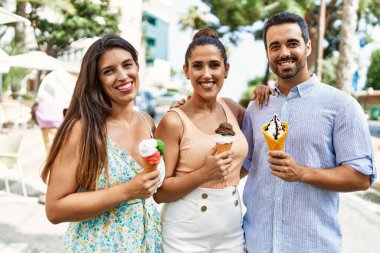 Üç İspanyol arkadaş gülerek şehirde dondurma yiyor..