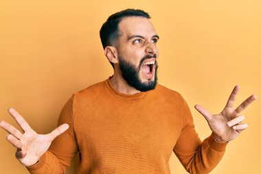 Sakallı genç adam, sıradan bir kazak giyiyor. Deli gibi bağırıyor, agresif bir ifadeyle bağırıyor ve kollarını kaldırıyor. hüsran kavramı. 