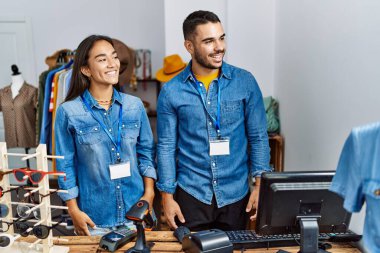 Perakende mağazasında çalışan genç ırklar arası insanlar gülümseme ve doğal ifadeyle yan yana bakıyorlar. Kendinden emin gülen. 