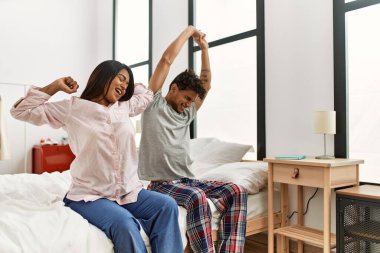 Genç Latin çift, yatak odasındaki yatakta esniyor ve kollarını esnetiyorlar..