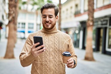 Kafkasyalı genç adam akıllı telefon kullanıyor. Şehirde kahve içiyor..