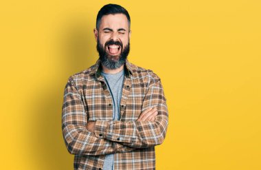 Kollarını kavuşturmuş sakallı İspanyol bir adam komik bir ifadeyle dilini dışarı çıkarıyor.. 