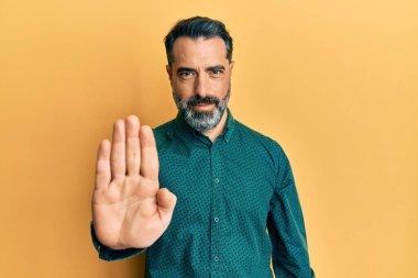 Orta yaşlı, sakallı, gri saçlı iş kıyafetleri giyen bir adam avucunun içi gibi şarkı söylemeyi kesiyor. Yüzünde olumsuz ve ciddi bir jest olan uyarı ifadesi. 