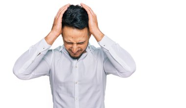 Genç Arap adam gündelik kıyafetler giyip baş ağrısı çekiyor. Acı ve migren yüzünden çaresiz ve stresli. Eller başının üstünde.. 