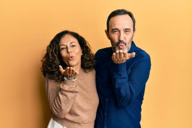 Orta yaşlı İspanyol çift, gündelik kıyafetler giyip kameraya bakıyor ve havada öpüşüyorlar. Güzel ve seksi oluyorlar. aşk ifadesi. 