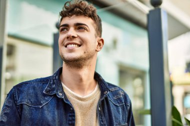 Genç İspanyol adam gülümseyerek şehirde mutlu mesut dikiliyor.