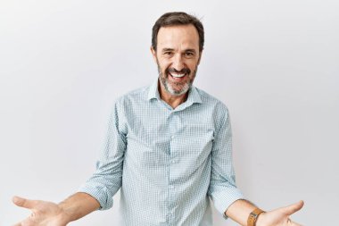 Orta yaşlı, sakallı, izole edilmiş arka planda duran neşeli kolları açık bir şekilde gülümseyen, dostça bir hoş geldin, olumlu ve kendinden emin selamlaşma. 