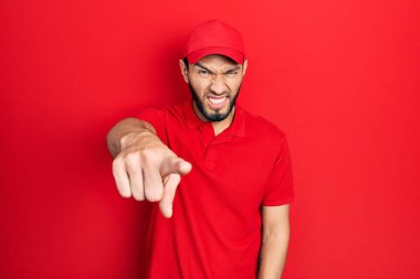 Sakallı, teslimat üniformalı ve şapkalı İspanyol adam kameraya kızgın ve sinirli bir şekilde bakıyor. 