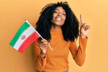 Kürdistan bayrağı tutan afro saçlı Afrikalı Amerikalı bir kadın bir fikir veya soruyla gülümsüyor ve mutlu bir yüzle işaret ediyor. 