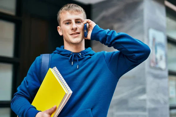 Joven Estudiante Rubio Hablando Smartphone Sosteniendo Cuaderno Universidad —  Fotos de Stock