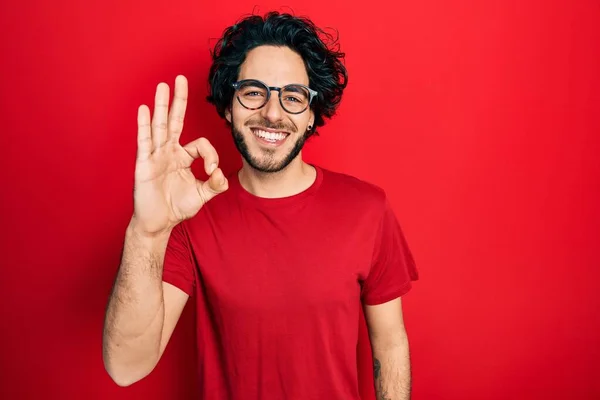 カジュアルなTシャツを着たハンサムなヒスパニック系の男性と 手と指でOkサインをして積極的に笑顔メガネ 成功した表現 — ストック写真
