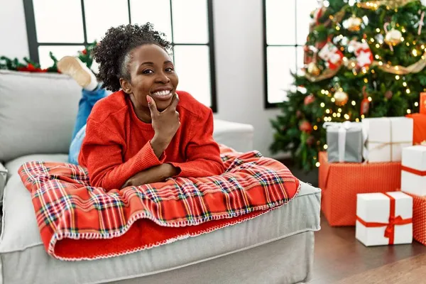 Joven Mujer Afroamericana Tumbada Sofá Por Árbol Navidad Mirando Confiado — Foto de Stock