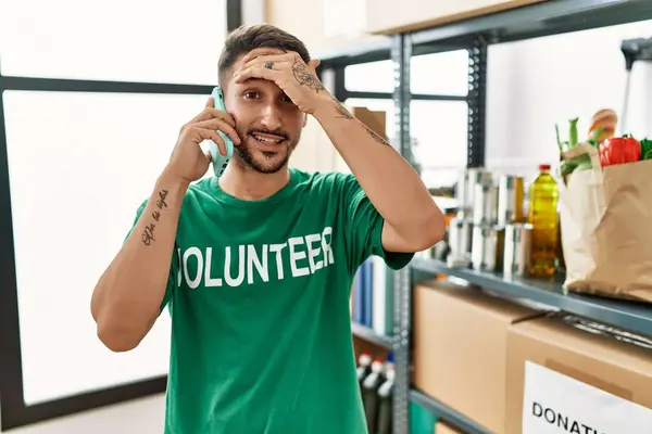 Young Hispanic Man Wearing Volunteer Shirt Speaking Phone Stressed Frustrated — Foto de Stock