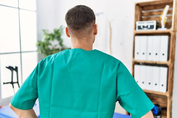 Young Physiotherapist Man Working Pain Recovery Clinic Standing Backwards Looking — Φωτογραφία Αρχείου