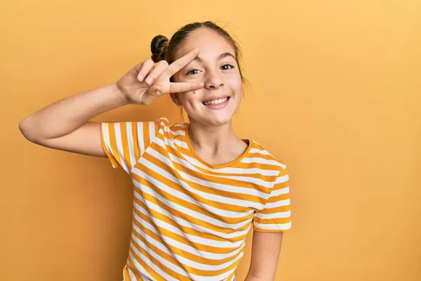 줄무늬 티셔츠를 아름다운 갈색의 소녀가 손가락으로 얼굴을 평화의 상징으로 승리를 — 스톡 사진