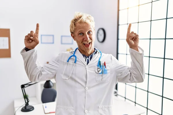 Young Blond Man Wearing Doctor Uniform Stethoscope Clinic Smiling Amazed — Stockfoto