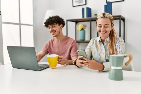 Unga Par Använder Laptop Och Smartphone Dricka Kaffe Hemma — Stockfoto