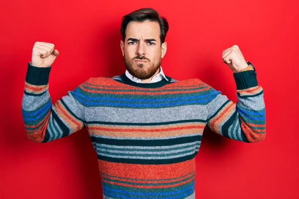 エレガントなウールの冬のセーターを着て髭を生やしたハンサムな白人男性は腕の筋肉を誇りに思って笑顔を見せます フィットネスのコンセプト — ストック写真