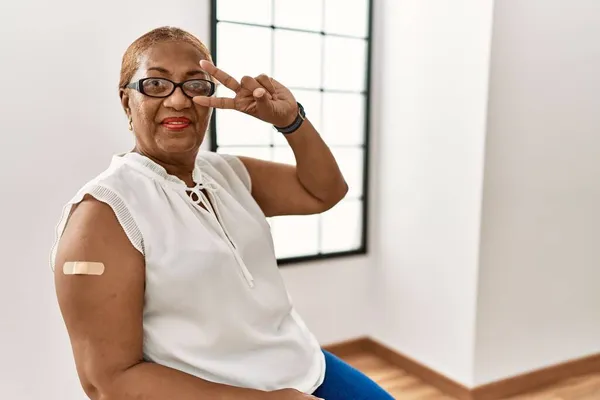 Starší Hispánská Žena Dostává Vakcínu Ukazující Ruku Náplastí Mírumilovný Symbol — Stock fotografie