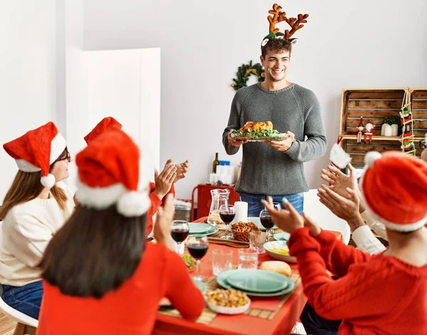 人々のグループを会議拍手とテーブルの上に座っている 男立って 家でクリスマスを祝うロースト七面鳥を保持 — ストック写真