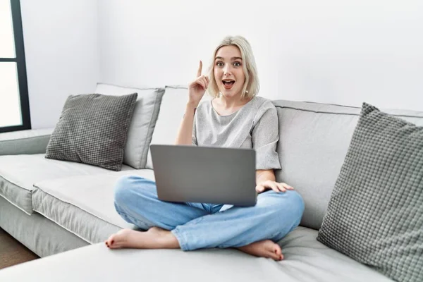 Young Caucasian Woman Using Laptop Home Sitting Sofa Pointing Finger — Stok fotoğraf