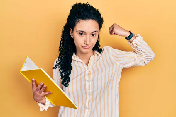 Young Hispanic Woman Curly Hair Holding Book Strong Person Showing — Stockfoto