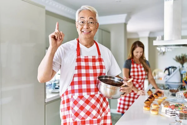 Middle Age Hispanic Couple Wearing Apron Cooking Homemade Pastry Surprised — Stock Photo, Image