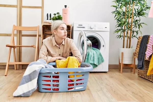 年轻的高加索女人靠在洗衣房的洗衣篮上 — 图库照片