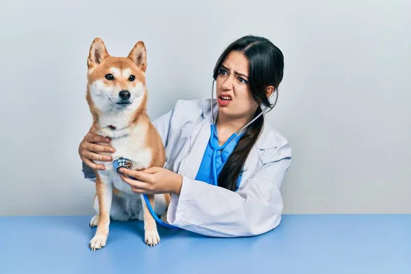 他那漂亮的惊慌失措的兽医女人检查狗的健康状况时 脸上既无知觉又困惑的表情 怀疑概念 — 图库照片