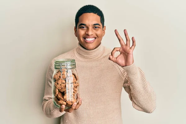 Genç, yakışıklı İspanyol adam elinde bir kavanoz çikolatalı kurabiye tutuyor. Parmaklarıyla imza atıyor, gülümsüyor. Mükemmel bir sembol. 