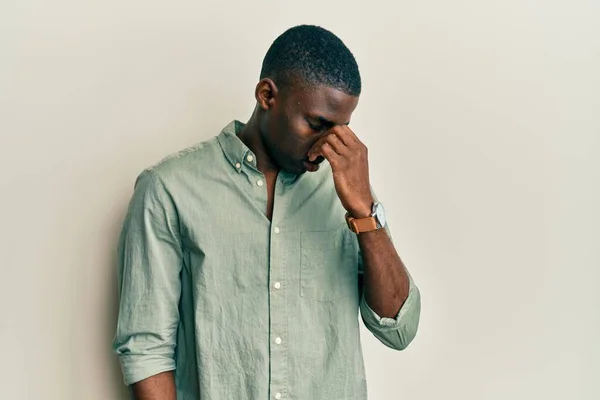 若いアフリカ系アメリカ人の男性は カジュアルな服を着て疲れ鼻や目をこすり疲労感や頭痛を感じる ストレスとフラストレーションの概念 — ストック写真