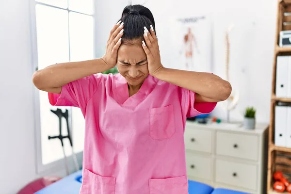 在疼痛恢复诊所工作的年轻恐慌女人 由于疼痛和偏头痛 绝望和压力重重 手放在头上 — 图库照片