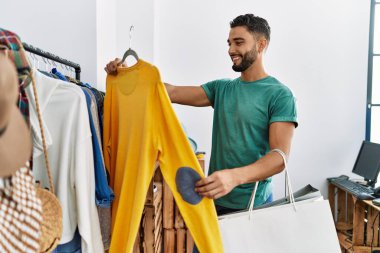 Genç Arap müşteri kıyafet mağazasında kendine güvenen bir alışveriş yapıyor.