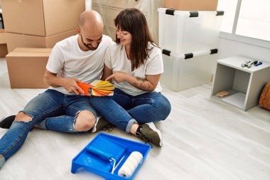 Genç İspanyol çift mutlu bir şekilde gülümsüyor. Yeni evinde boya rengi seçiyor..