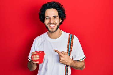 Yakışıklı İspanyol bir adam bir fincan kahve içiyor. Gülümsüyor, mutlu bir şekilde elini ve parmağını gösteriyor. 