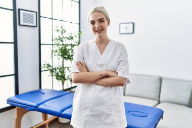 Young caucasian physiotherapy woman working at home happy face smiling with crossed arms looking at the camera. positive person. 