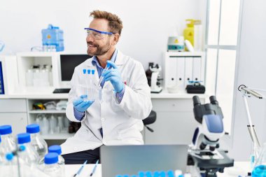 Orta yaşlı, labaratuarda çalışan bilim adamı üniforması giyen bir İspanyol.