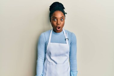 Saçları örgülü, daha temiz önlük takan, eldivenli sürpriz ifadeden, korkudan ve heyecandan şok olmuş Afrikalı Amerikalı kadın.. 