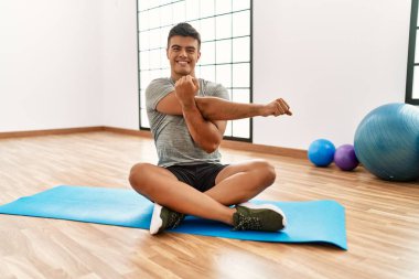 Genç İspanyol adam gülümsüyor spor merkezinde esniyor.