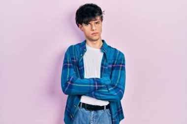 Yakışıklı hippi genç adam günlük beyaz tişört ve klasik gömlek giyiyor şüpheci ve gergin, yüzünde çapraz kollu tasvip etmeyen bir ifade var. negatif kişi. 