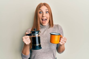 Genç İrlandalı kadın İtalyan kahvesi içiyor çılgınlığı kutluyor ve başarıya hayret ediyor gözleri açık heyecanla haykırıyor. 