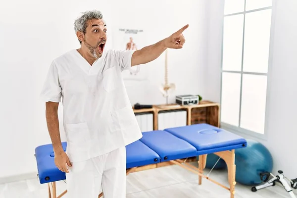 Middle Age Hispanic Therapist Man Working Pain Recovery Clinic Pointing — Stockfoto
