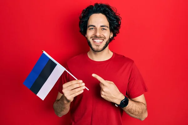 Snygg Latinamerikansk Man Med Estoniflagga Som Ler Glad Pekar Med — Stockfoto