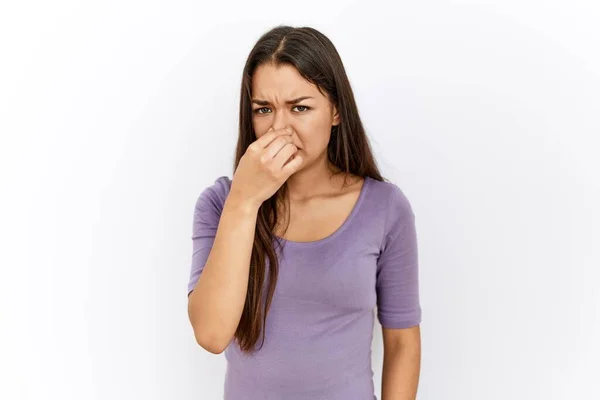 若いブルネットの女性は 鼻の上に指で息を保持し 臭いと嫌な 耐え難い匂いを嗅ぐ孤立した背景に立っている 臭いが悪い — ストック写真