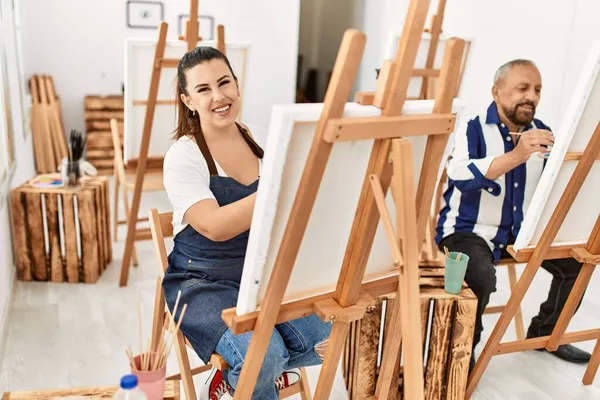 若い芸術家の女性とアートスタジオの教室でシニア画家の男性ブラシと油絵でキャンバス上の絵画 — ストック写真